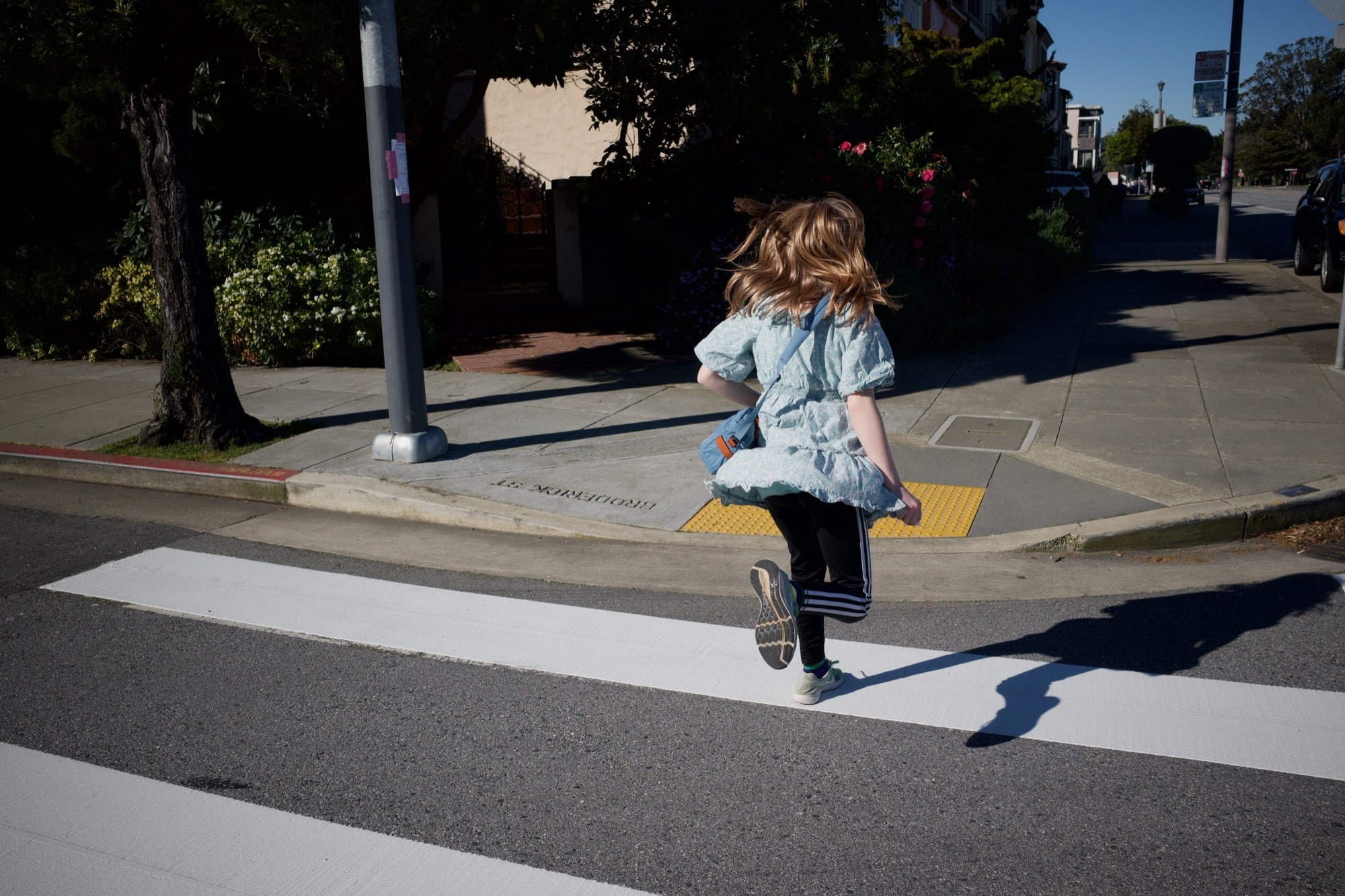Kiddo jumping on the white stripes that make up a crosswalk.
