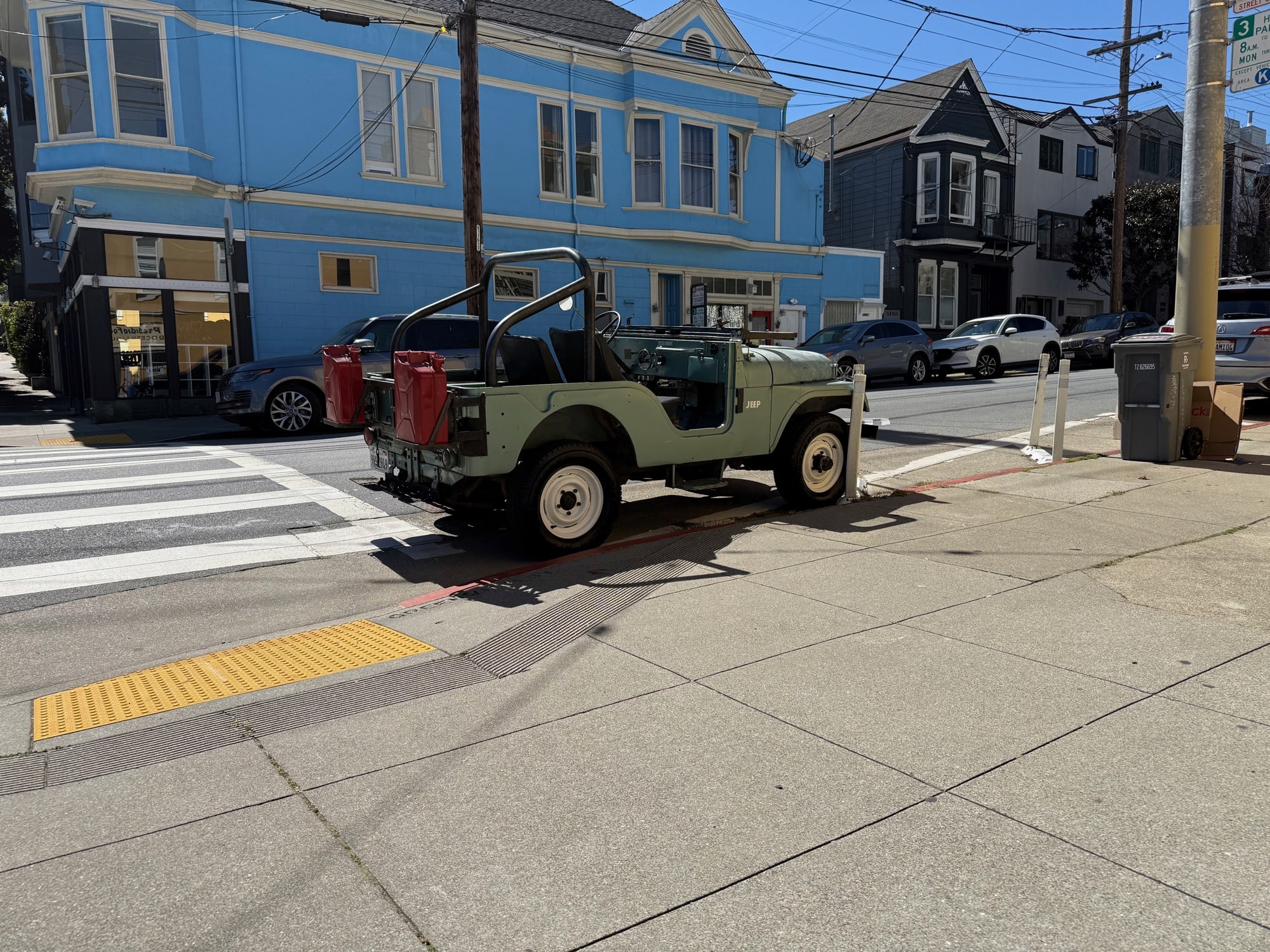 A classic Willys Jeep parked in the street outside of a corner store.