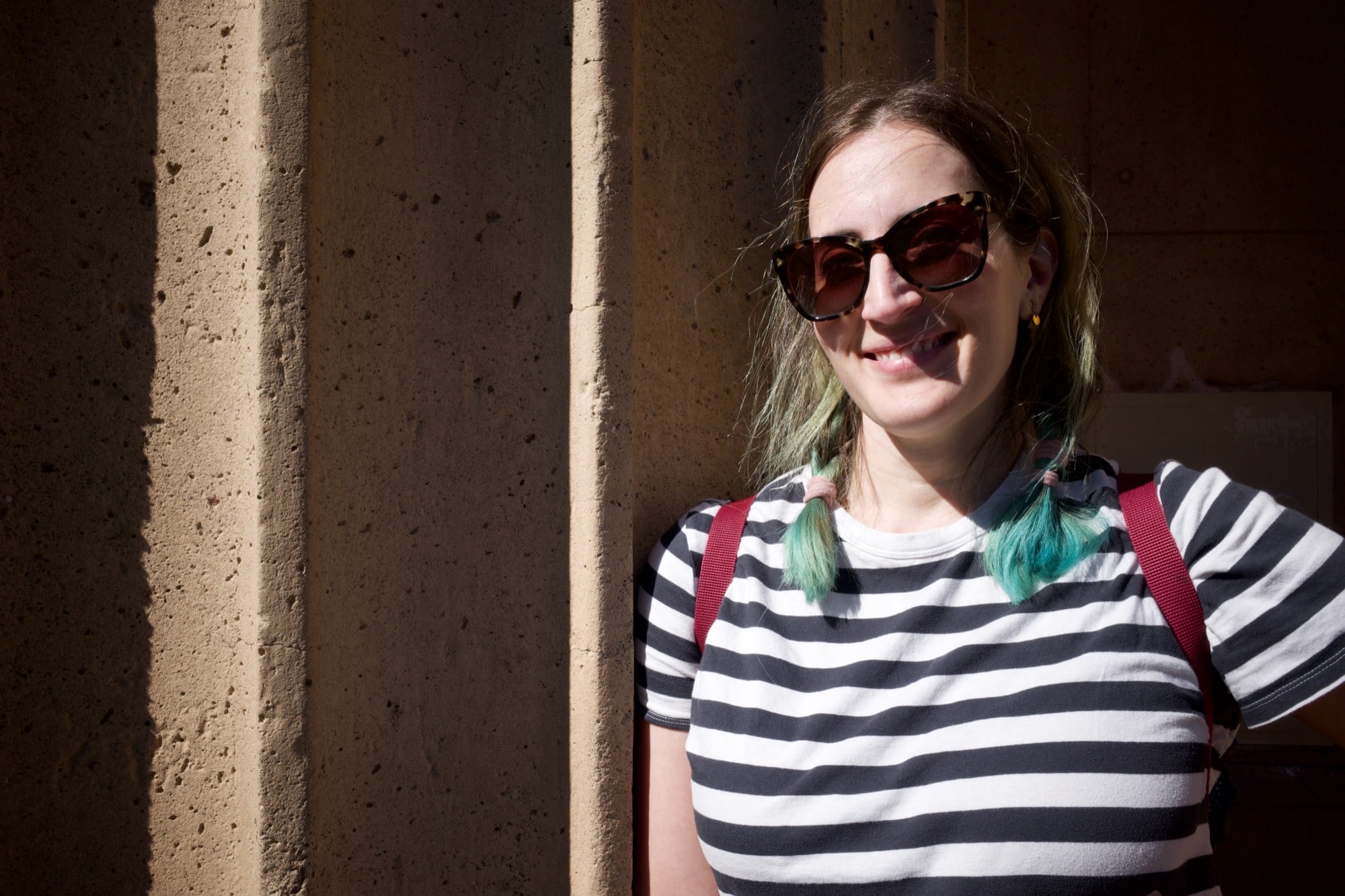 Molly smiling and leaning against a Romanesque column